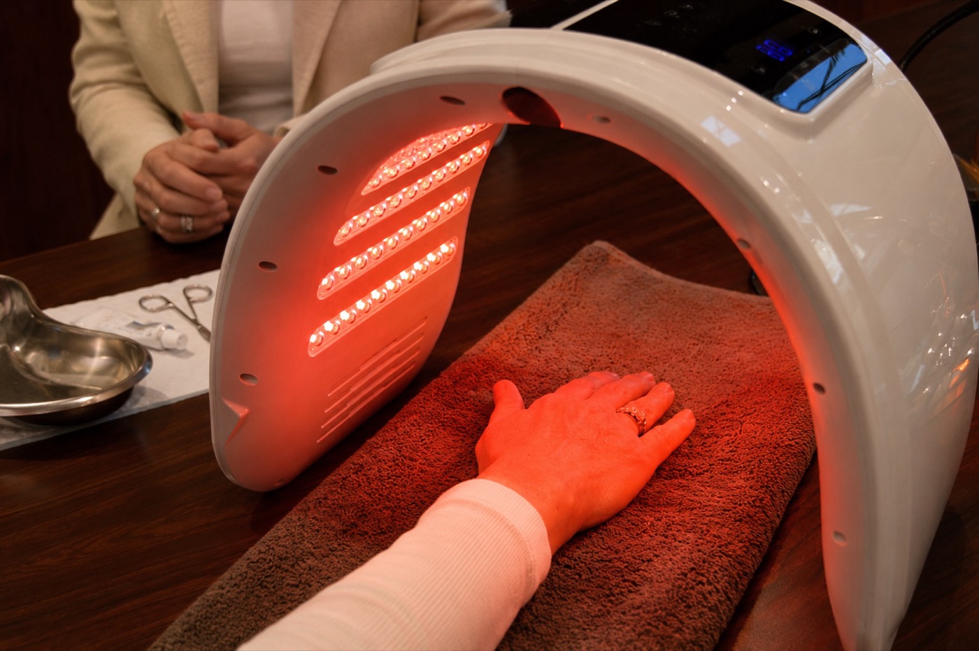 A client's hand under a red light therapy device