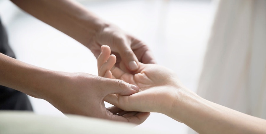 A therapist gently holding a client's hand